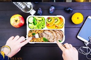 top view showing hands eating healthy lunch with bulgur meat fresh vegetables fruit wooden table fitness healthy lifestyle concept lunchbox top view