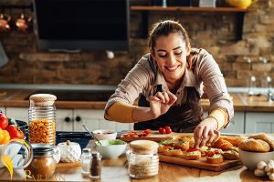 young smiling woman making bruschetta with healthy ingredients while preparing food kitchen