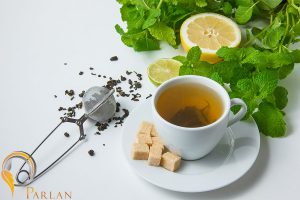 high angle view cup tea with lemon sugar mint leaves white surface horizontal
