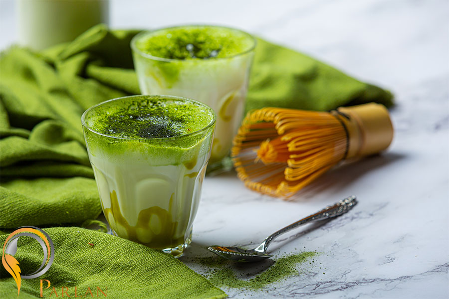 hot green tea glass with cream topped with green tea decorated with green tea powder