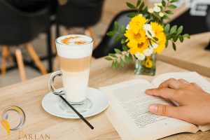 person reading book near coffee cup desk caf
